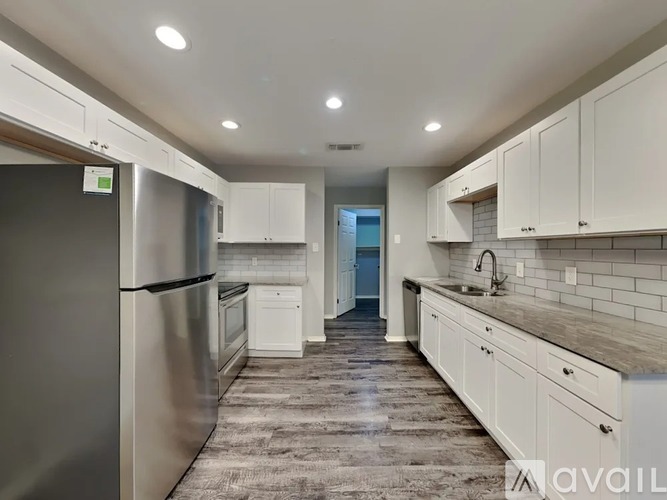 A modern kitchen with white cabinets and a stainless steel refrigerator.