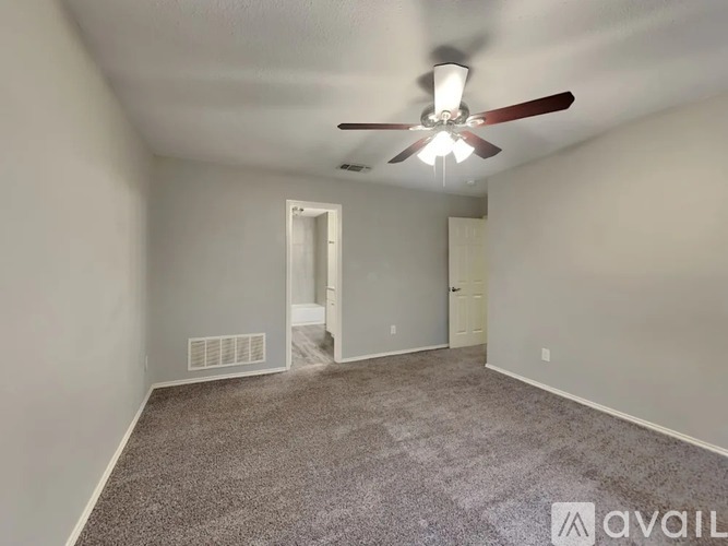 A room with a ceiling fan and carpeted floor.