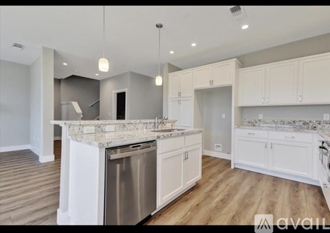 A modern kitchen with white cabinets and a marble countertop.