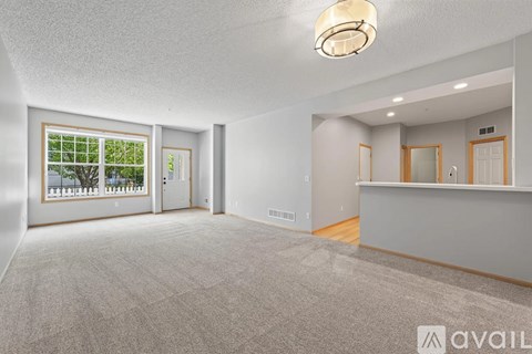 A spacious room with a carpeted floor, a ceiling light, and a window with a view of a balcony.