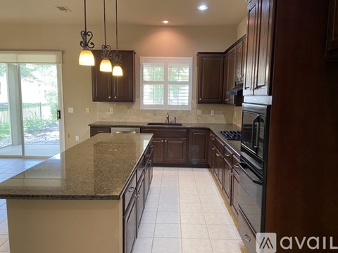 A kitchen with dark wood cabinets and a granite countertop.