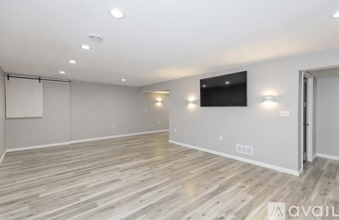 A spacious room with wooden flooring and a flat-screen TV mounted on the wall.