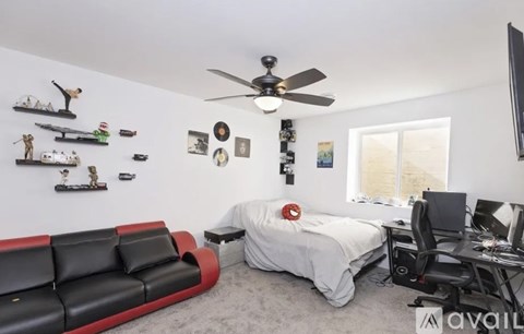 A bedroom with a bed, desk, and a red couch.
