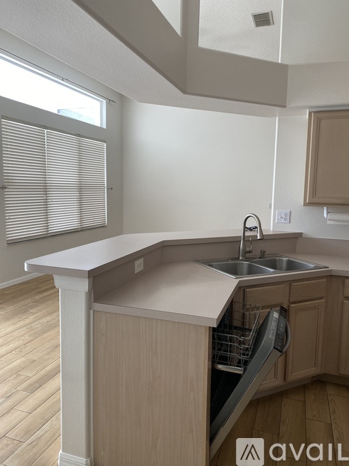 A kitchen with a sink and a window with blinds.