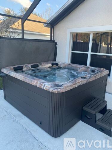 A hot tub is sitting on a patio with a glass enclosure.