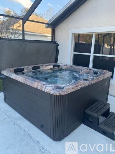 A hot tub is sitting on a patio with a glass enclosure.