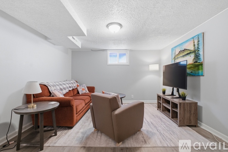 A living room with a brown couch, a chair, a coffee table, and a television.