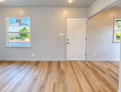 A room with a white door and a window showing a pool and a building.
