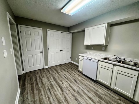 A kitchen with white cabinets and a wood floor.