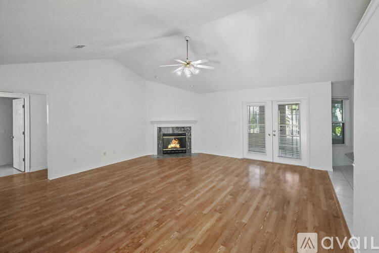 A spacious room with a fireplace and wooden flooring.