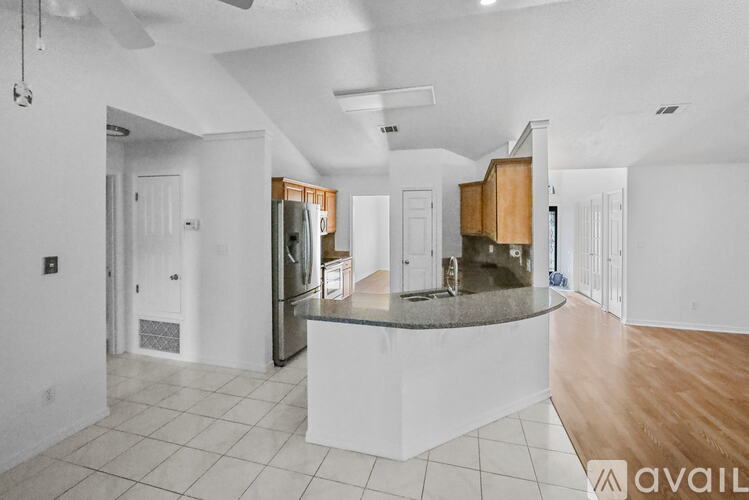A modern kitchen with a central island and a refrigerator to the left.