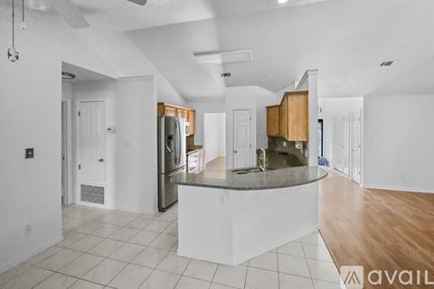 A modern kitchen with a central island and a refrigerator to the left.