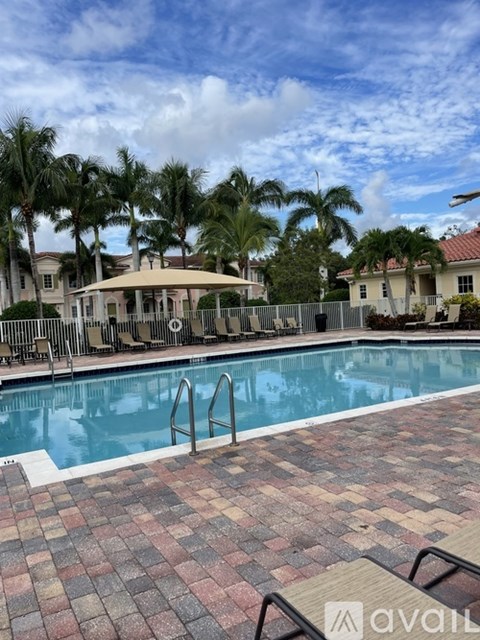 A pool surrounded by palm trees and a brick patio.