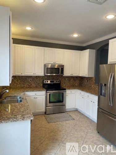 A kitchen with white cabinets and a granite countertop.