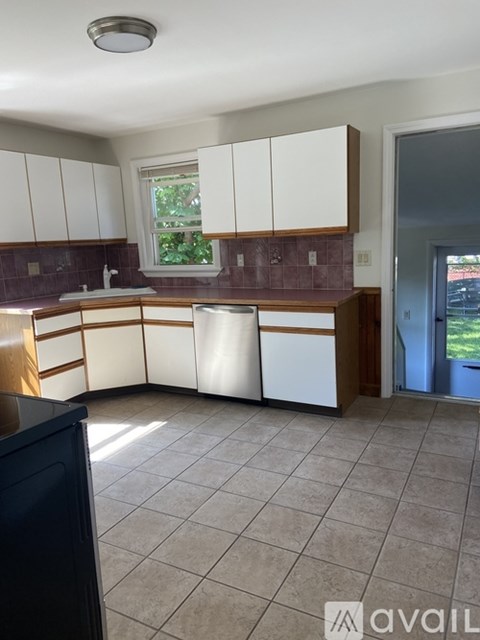 A kitchen with white cabinets and brown countertops.