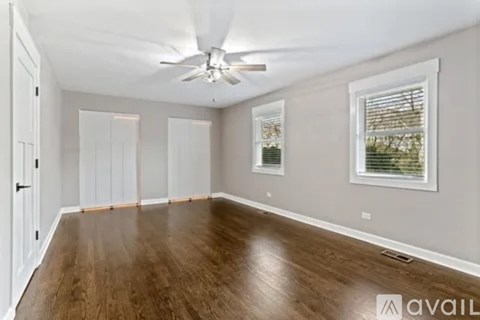 A spacious room with a ceiling fan and wooden flooring.