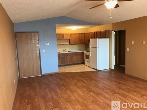 A kitchen with a white refrigerator and wooden floors.