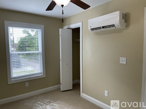 A room with a ceiling fan, window, and air conditioner unit.