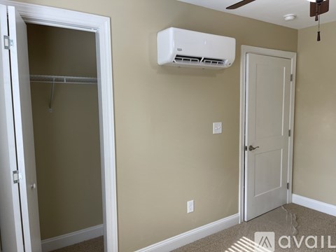 A wall-mounted air conditioner is installed above a door in a room.