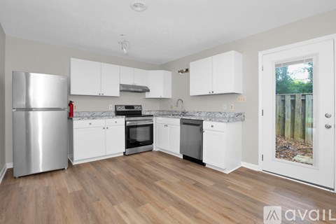 A kitchen with white cabinets and a wooden floor.