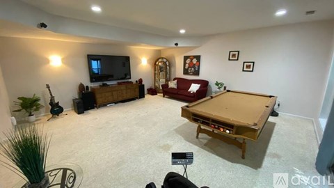 A room with a pool table, a television, and a couch.