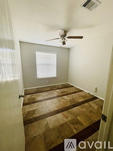 A room with a fan and a window with blinds.