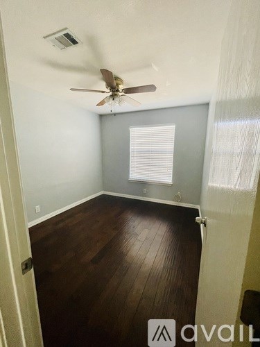 A room with a ceiling fan and wooden flooring.