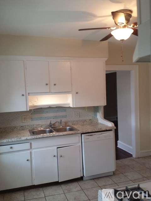 A kitchen with white cabinets and a marble counter top.