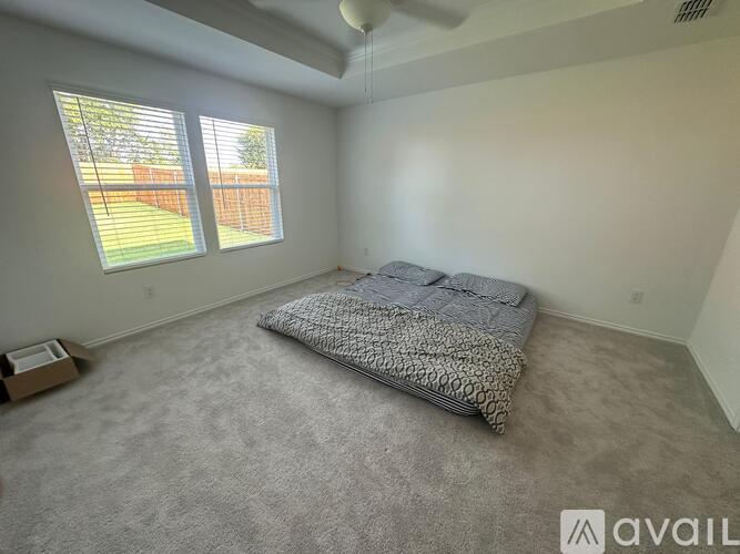 A bedroom with a bed and a window with blinds.