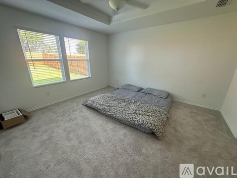 A bedroom with a bed and a window with blinds.