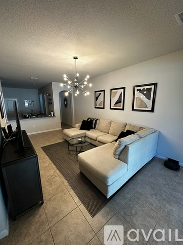 A living room with a white couch and a chandelier.
