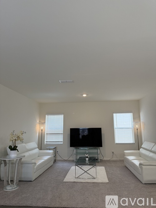 A living room with a television, two couches, and a glass coffee table.