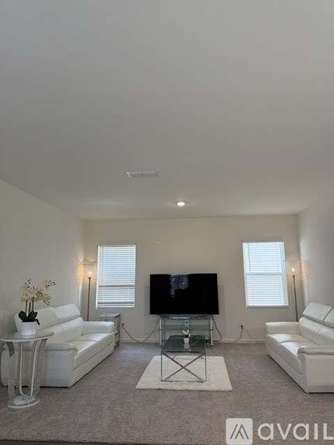 A living room with a television, two couches, and a glass coffee table.