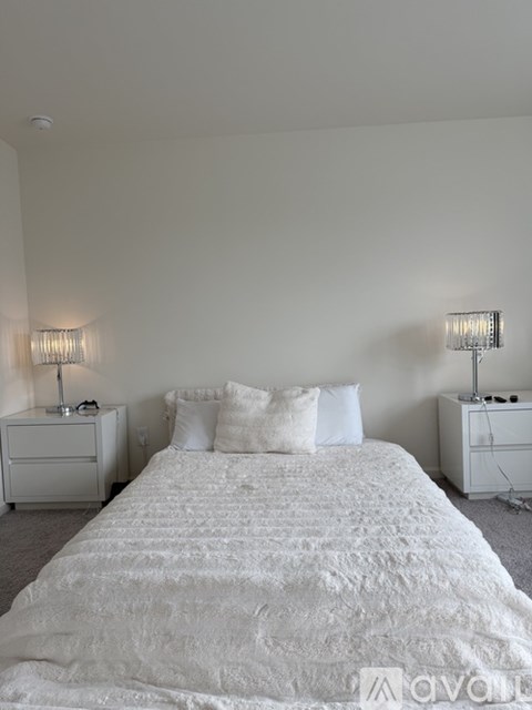 A bedroom with a large bed and two nightstands with lamps.
