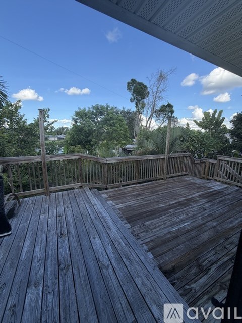 A wooden deck with a railing and trees in the background.