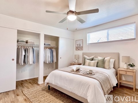 A bedroom with a bed, a ceiling fan, and a wardrobe.