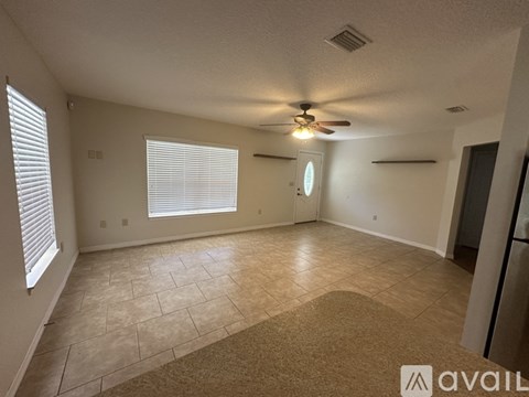 A spacious room with a ceiling fan and a rug on the floor.
