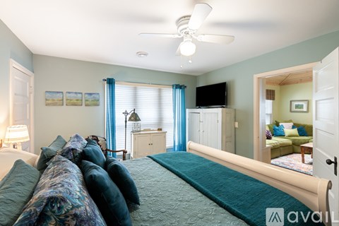 A bedroom with a large bed and a ceiling fan.