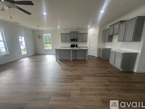 A spacious kitchen with wooden floors and a ceiling fan.