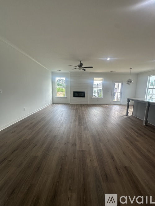 A spacious room with wooden flooring and a ceiling fan.