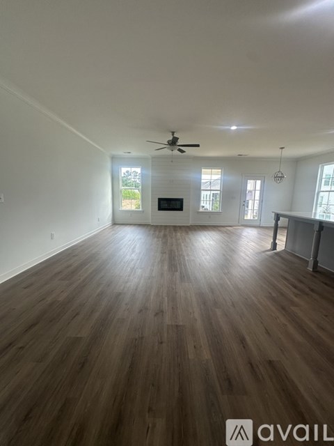 A spacious room with wooden flooring and a ceiling fan.