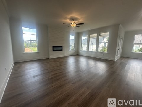 A spacious room with wooden flooring and a ceiling fan.