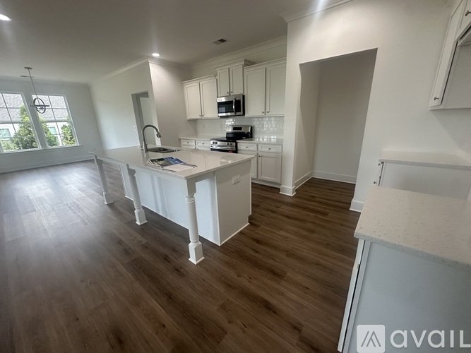 A kitchen with white cabinets and a wooden floor.
