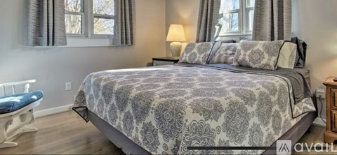 A bedroom with a large bed and a blue chair.