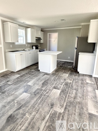 A kitchen with white cabinets and a grey floor.