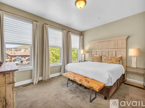 A bedroom with a large bed and a view of the outside through the window.