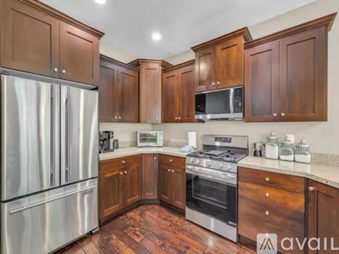 A kitchen with wooden cabinets and a stainless steel refrigerator.