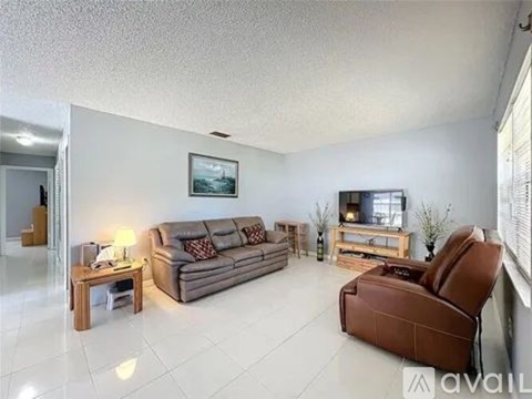 A living room with a grey couch, a brown leather chair, and a wooden coffee table.