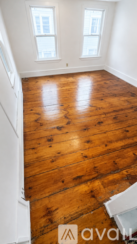 A wooden floor in a room with two windows.