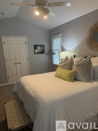 A bedroom with a bed, a ceiling fan, and a mirror on the wall.